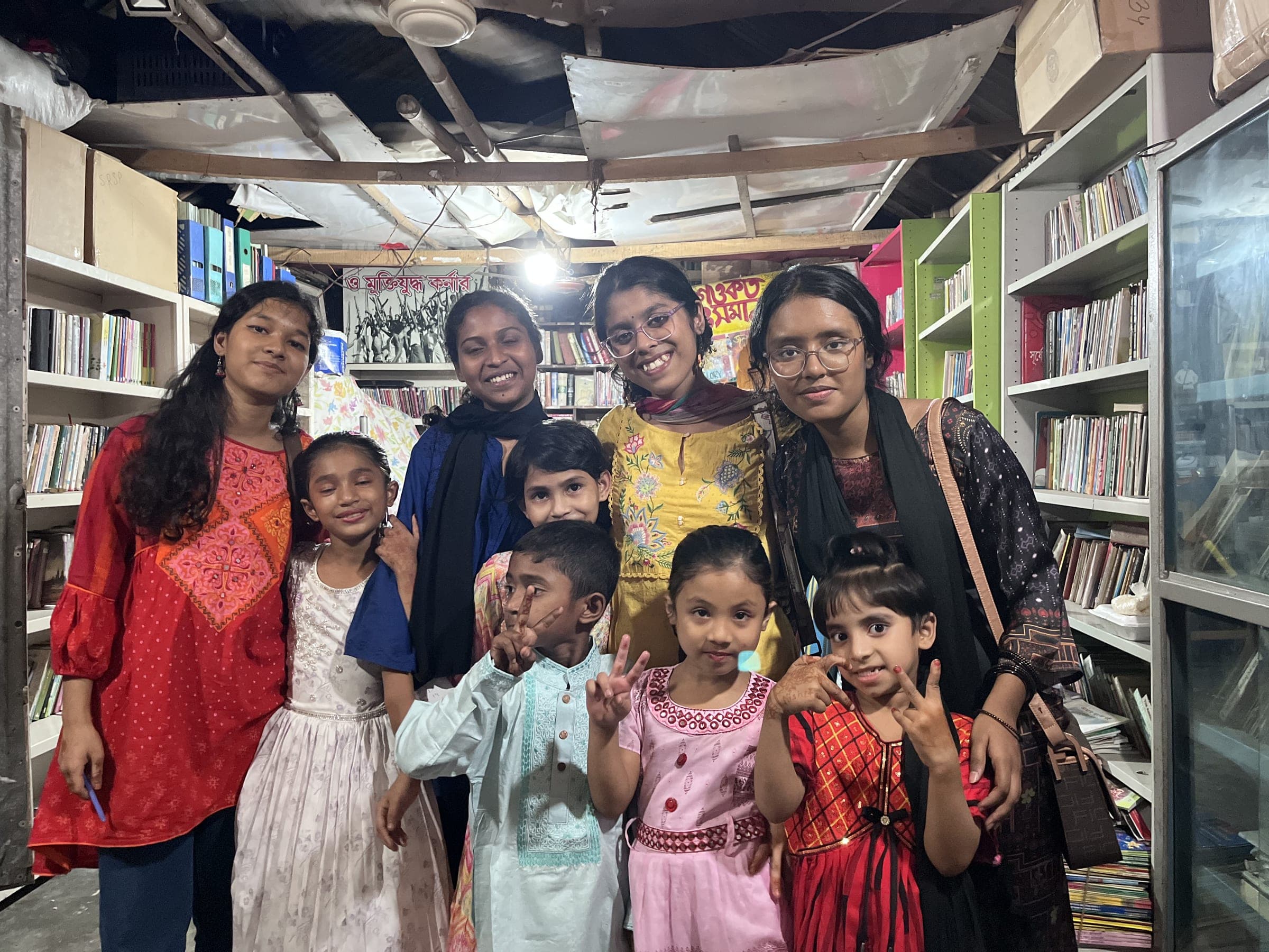 Volunteers and children standing together for a group photograph in the library