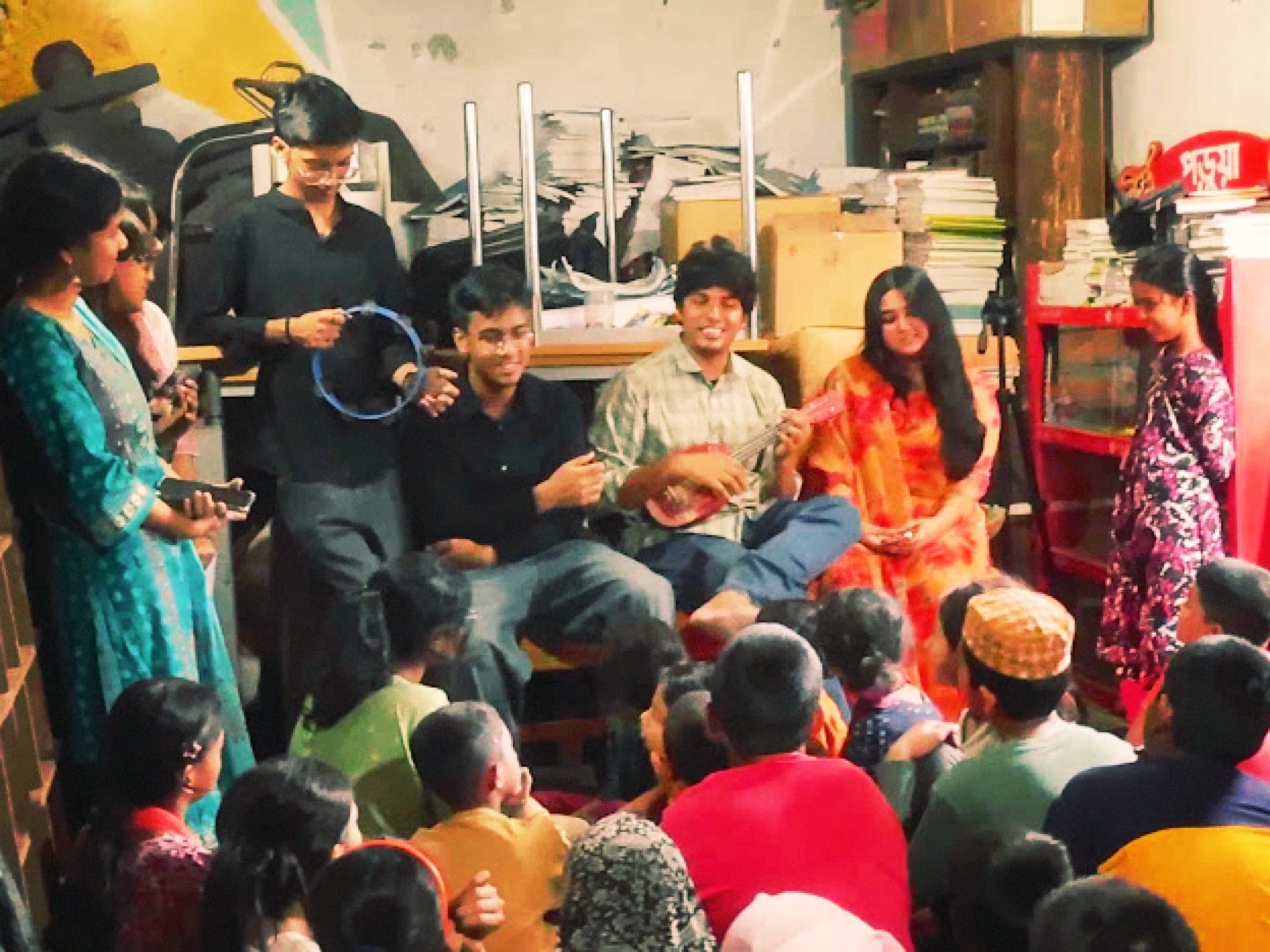 Volunteers sitting and talking with a large group of children in a library room